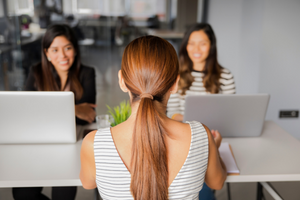 Female interviewer with their back turned facing two female interviewees